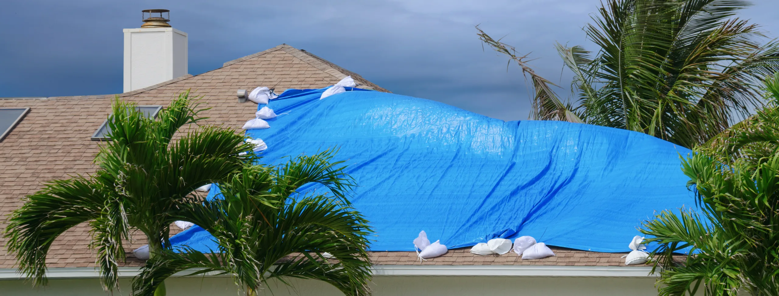 Storm damaged tile roof with tarpaulin.