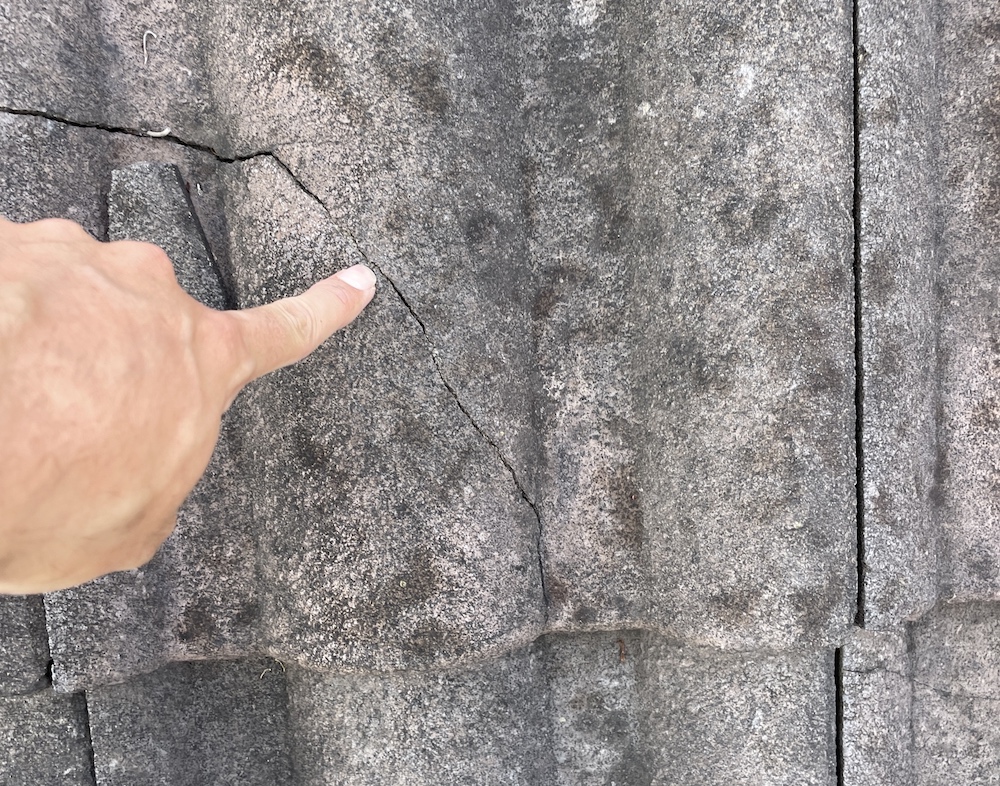 Roofer pointing to crack in tiles on roof