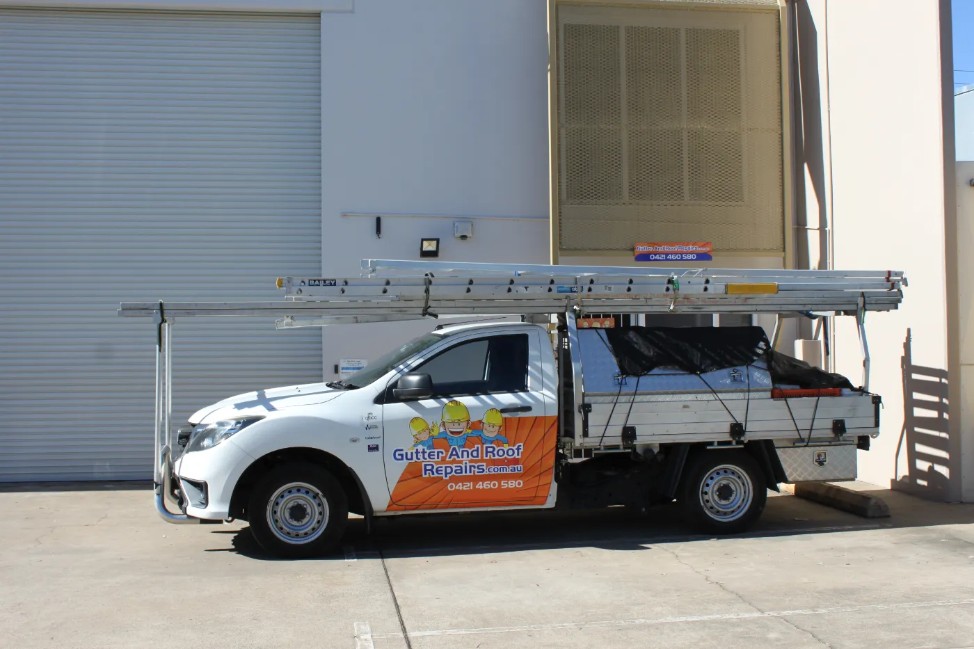 Gutter and Roof Repairs branded ute with ladder attached.