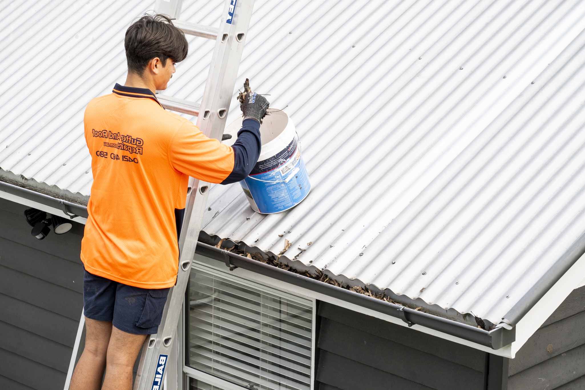 Gutter and Roof Repairs roofer cleaning metal gutters